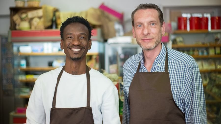 Two smiling shop owners behind the counter of a neighborhood store