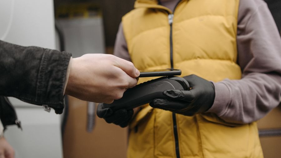 A customer tapping a card on a handheld reader outdoors