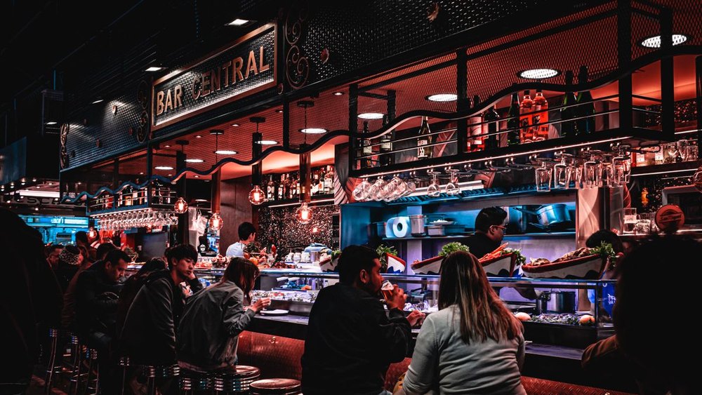 A busy restaurant and bar in the evening with guests at the counter